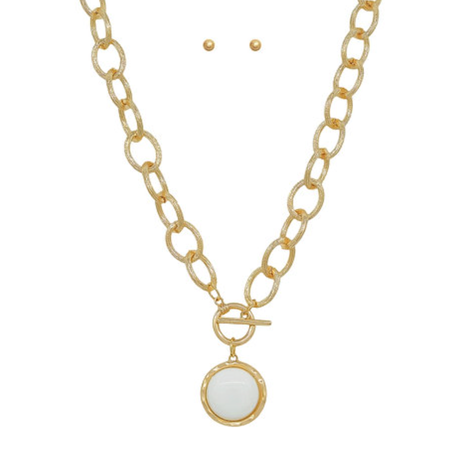 Gold chain necklace with a toggle clasp and a round white stone pendant, shown with two matching stud earrings.