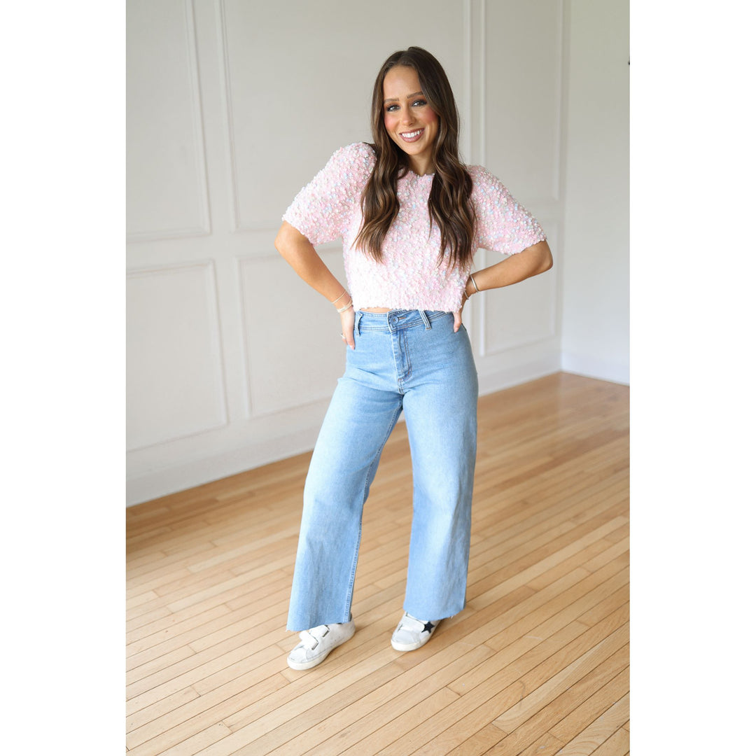 Woman wearing a pink sweater and light blue jeans 