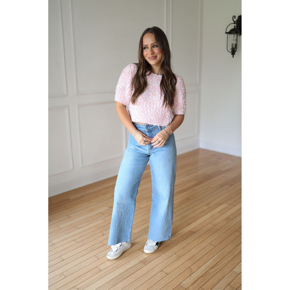 Woman wearing a pink sweater and light blue jeans 