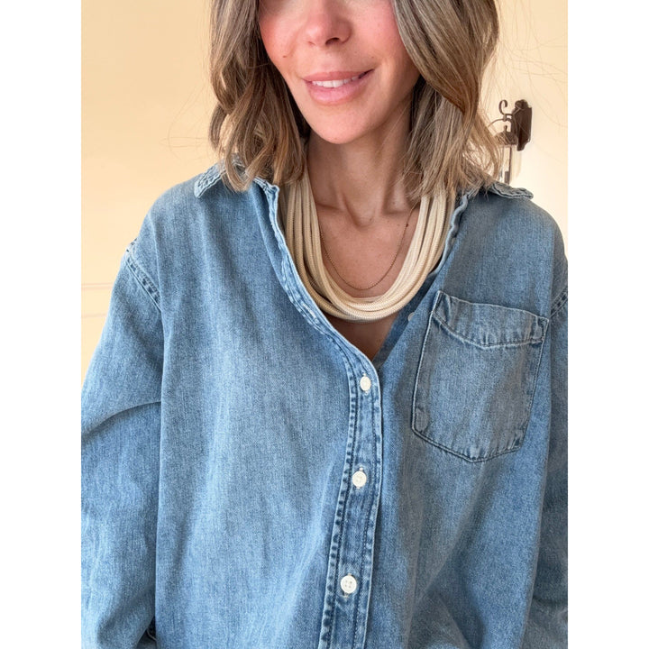 Woman wearing a blue denim shirt with a tan necklace