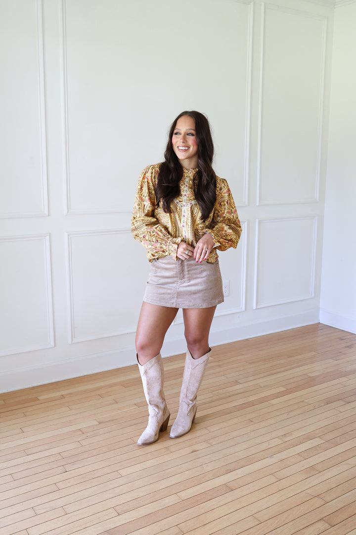 woman wearing mustard floral top and corduroy skort