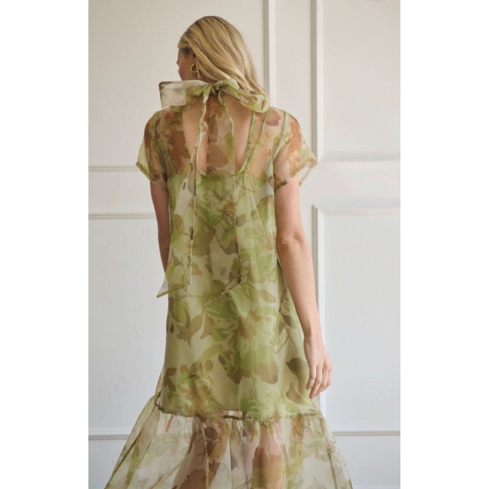 Woman wearing a green and brown patterned dress with sheer overlay 