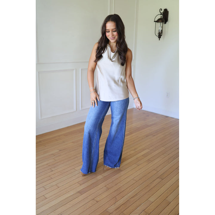 Woman wearing a champagne sleeveless top and blue jeans 