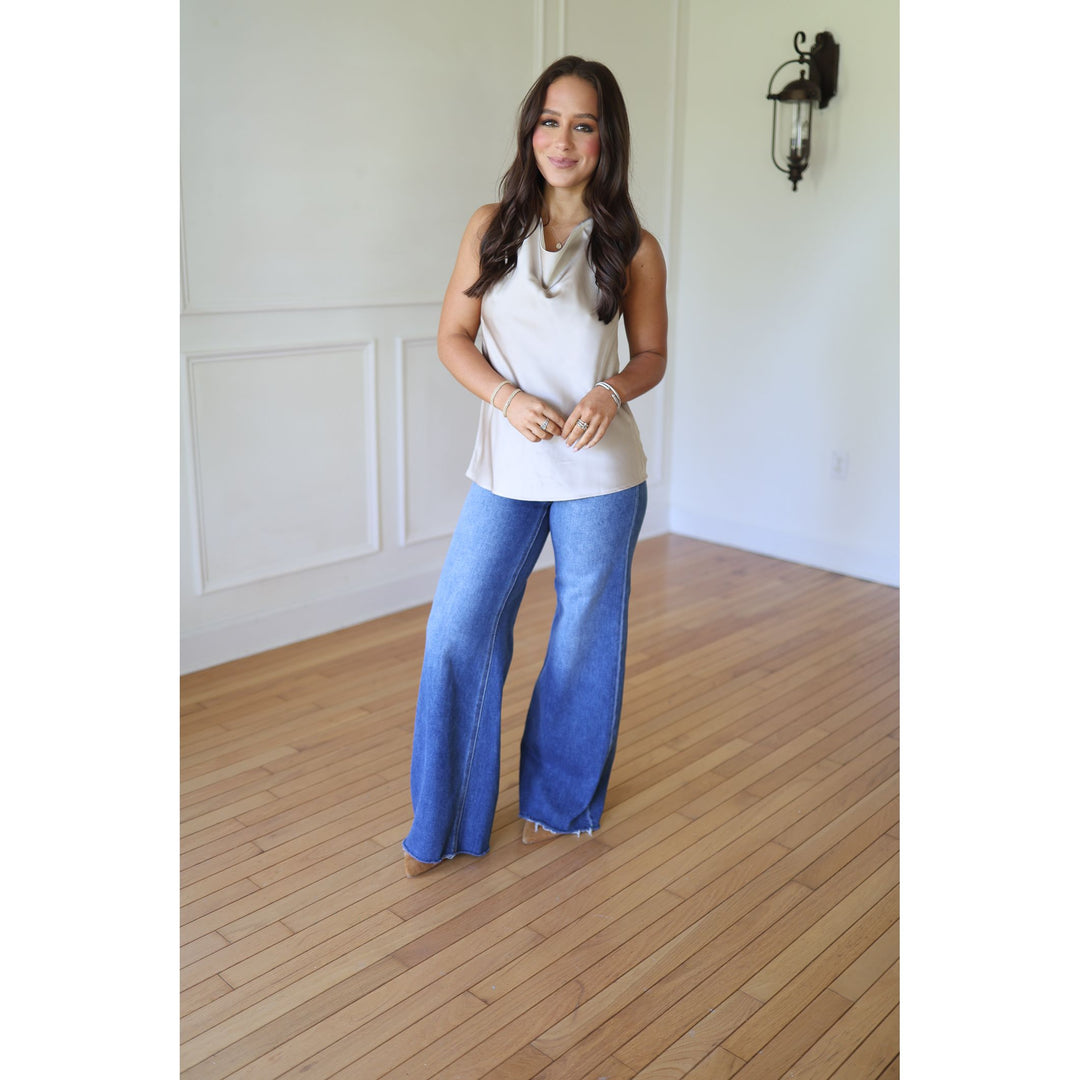 Woman wearing a champagne sleeveless top and blue jeans 