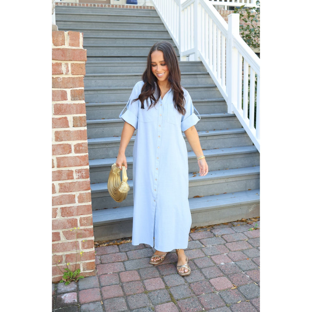 Woman in a light blue dress standing on a set of stairs.
