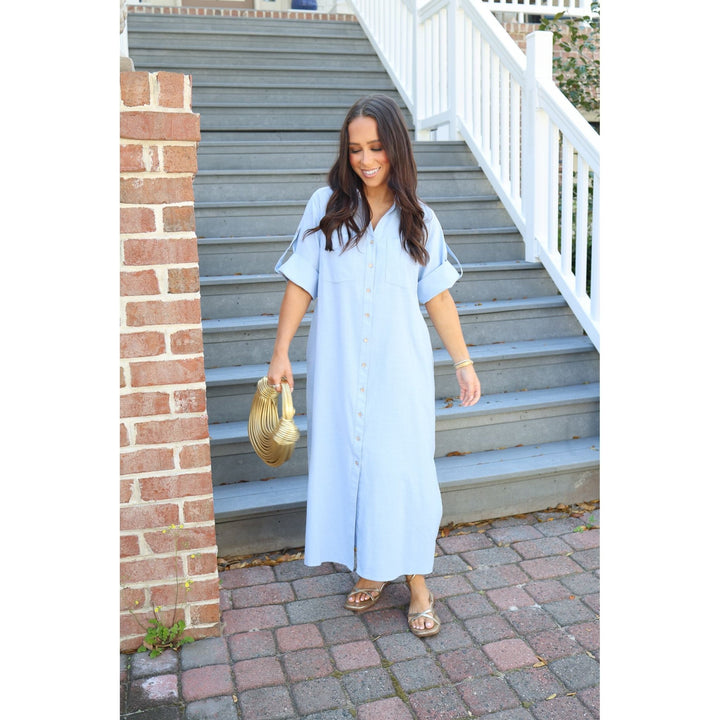 Woman in a light blue dress standing on a set of stairs.