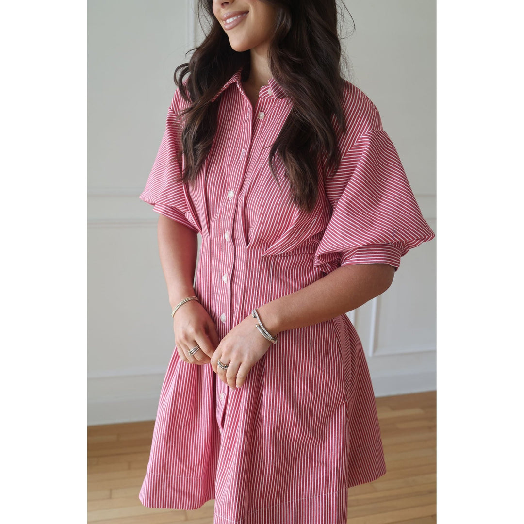 Woman wearing a pink striped dress indoors with a neutral background