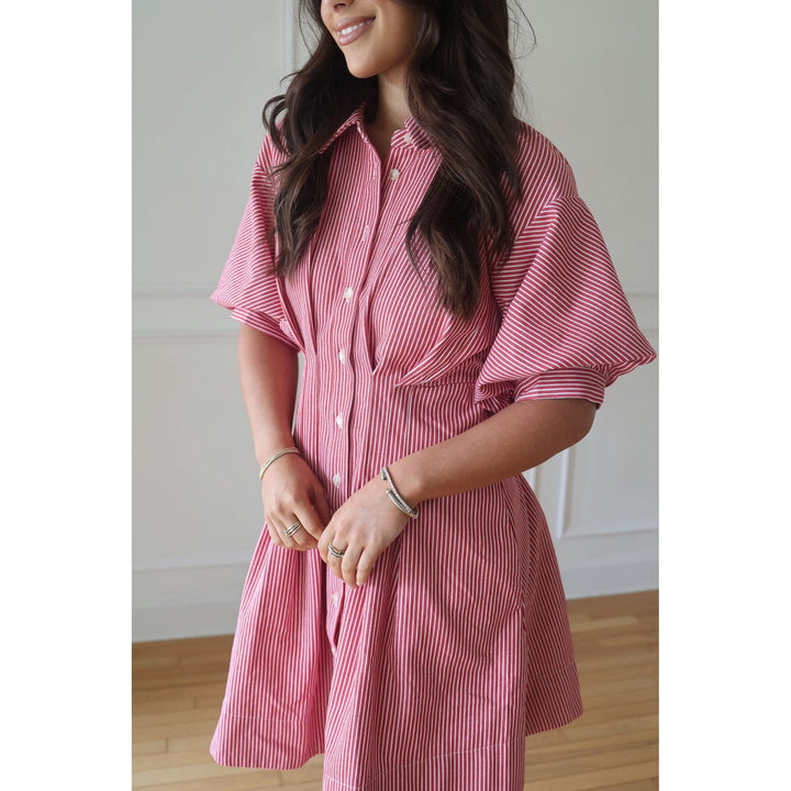Woman wearing a pink striped dress indoors with a neutral background