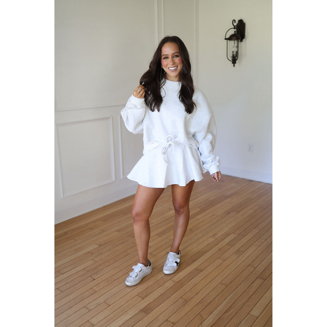 Woman wearing a gray outfit with a skirt 