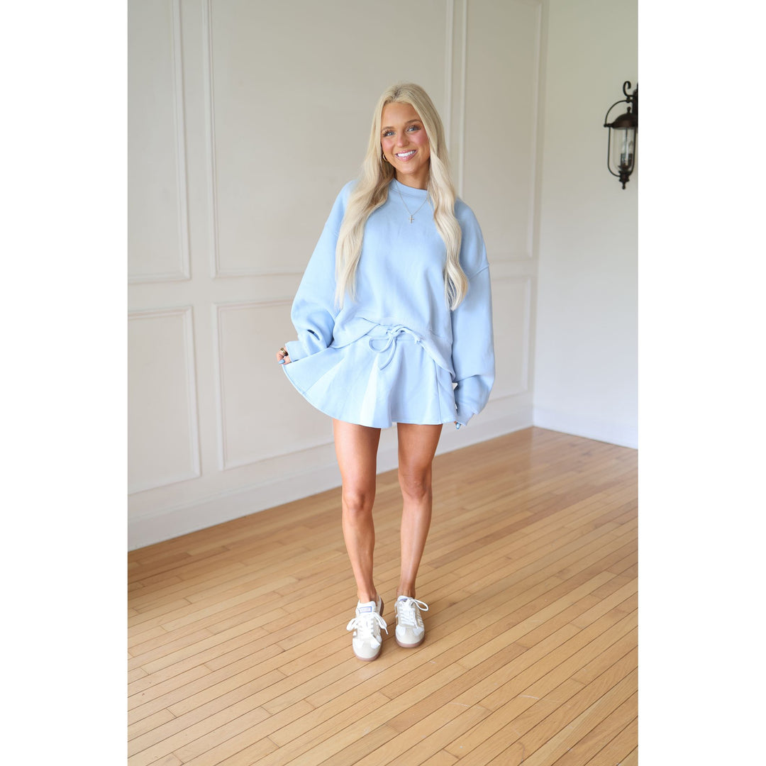 Woman wearing a light blue oversized sweater and skort