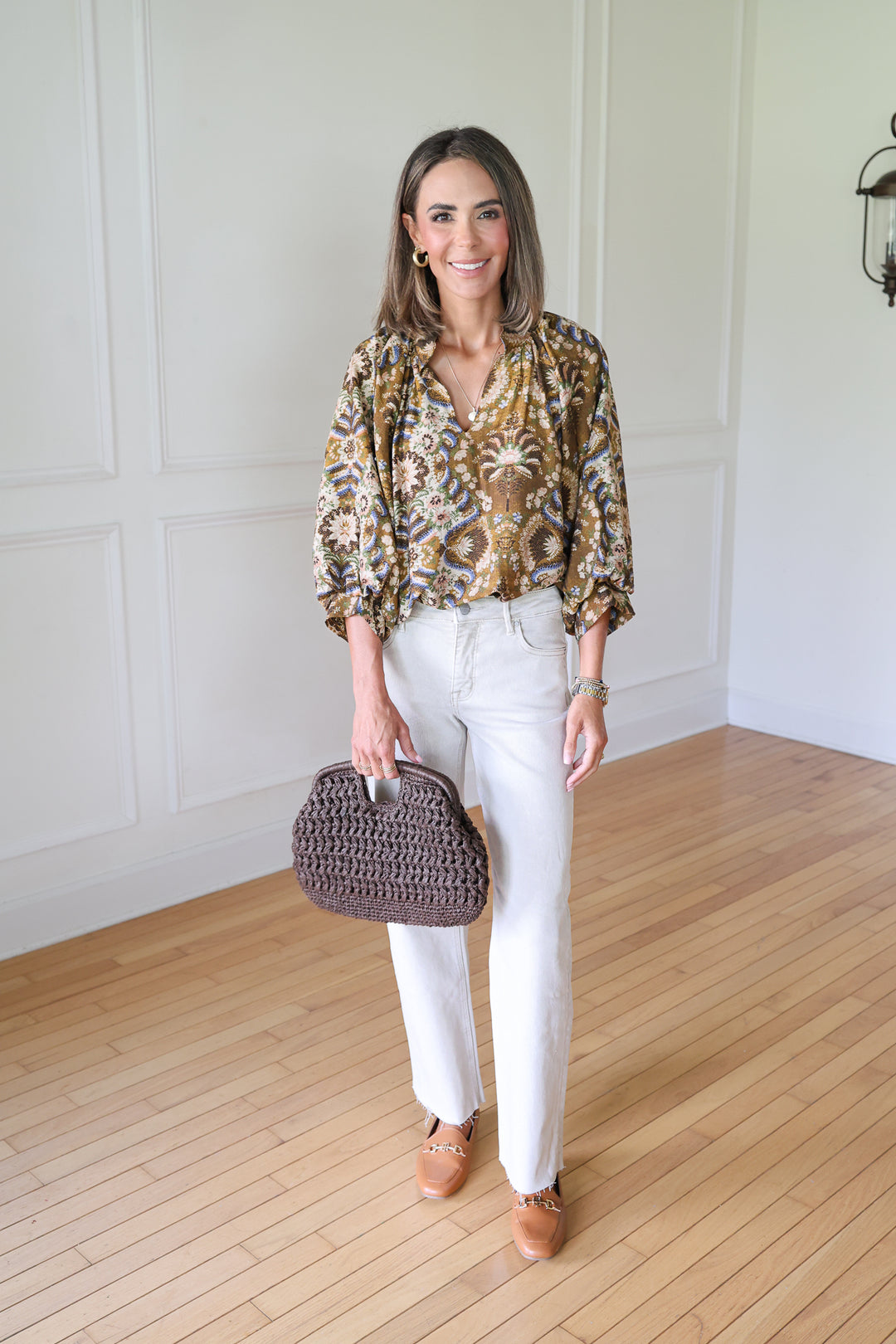 woman wearing brown floral top and tan jeans