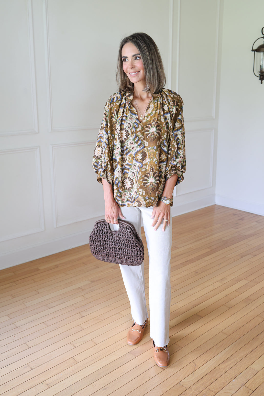 woman wearing brown floral top and tan jeans