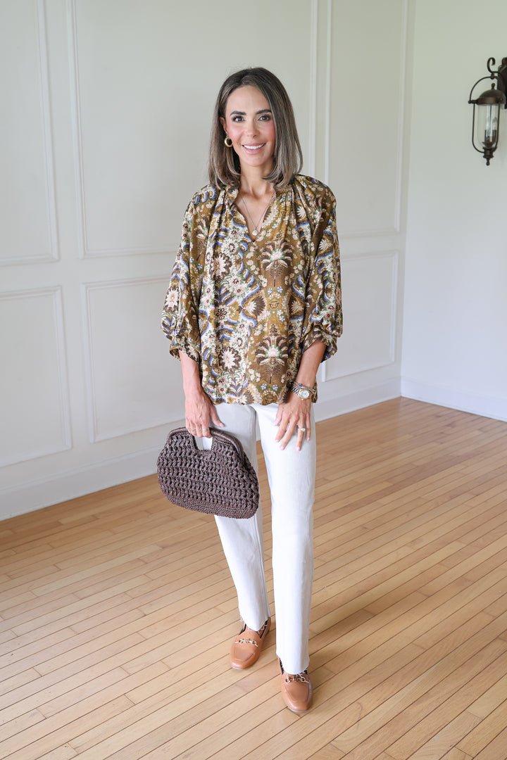 woman wearing brown floral top and tan jeans