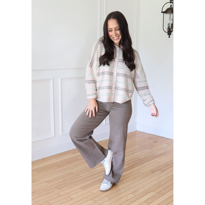 A woman modeling a beige and gray striped button-up shirt with wide-leg taupe pants and white sneakers