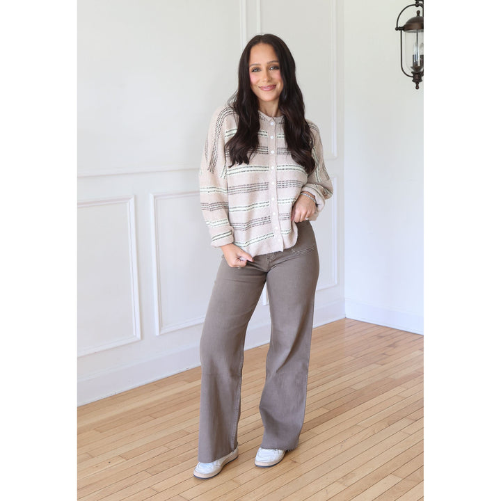 A woman modeling a beige and gray striped button-up shirt with wide-leg taupe pants and white sneakers
