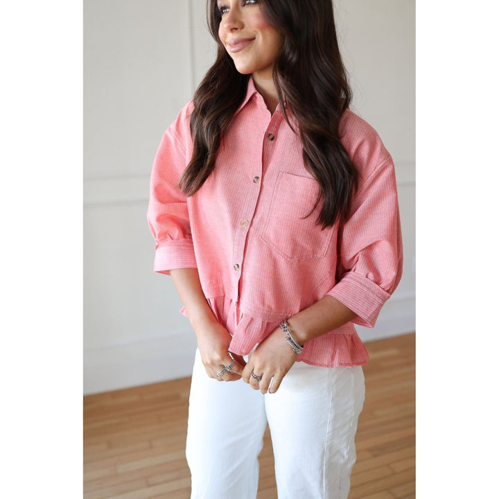 Woman wearing a pink shirt and white pants indoors