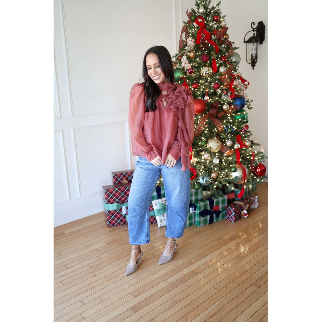 Woman standing in front of a decorated Christmas tree with presents underneath.