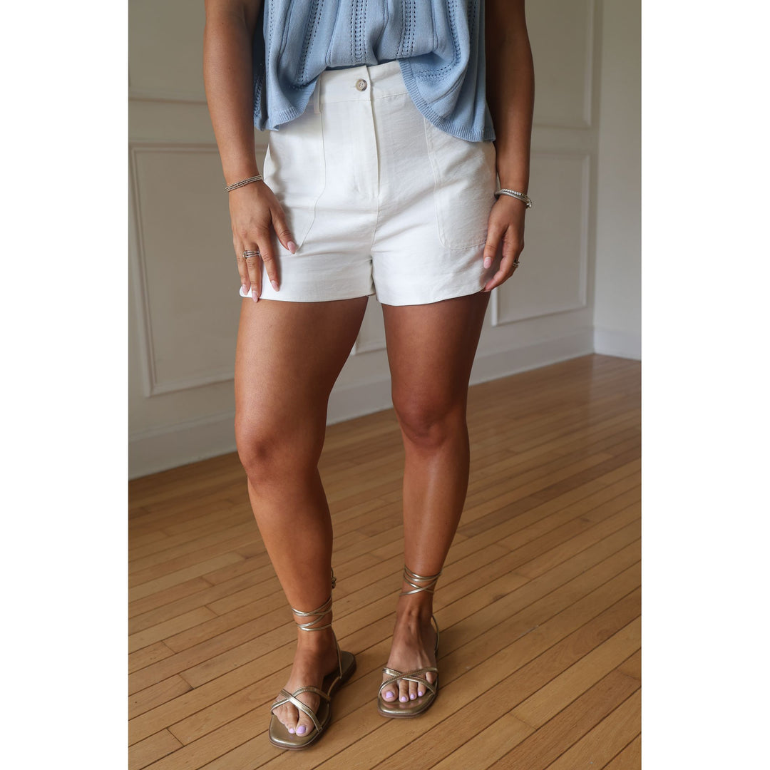 Person wearing white shorts and a blue top on a wooden floor.