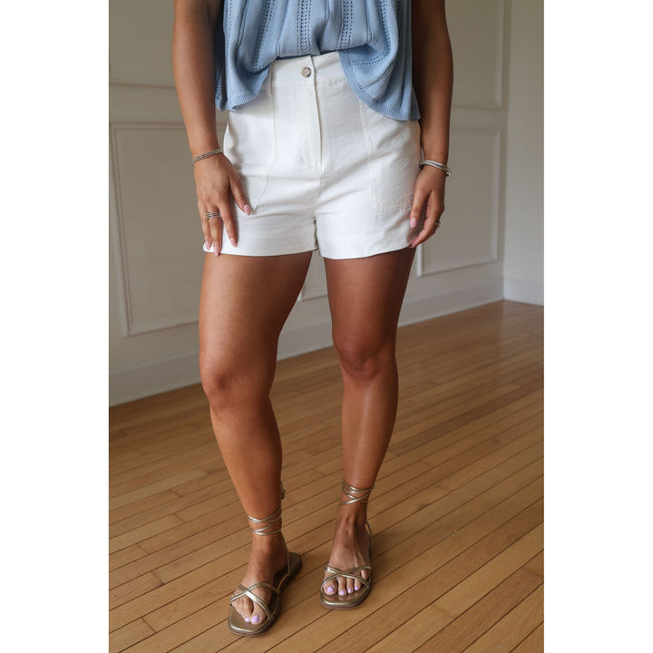 Person wearing white shorts and a blue top on a wooden floor.