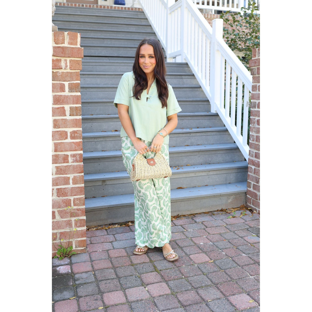 Woman in a light green outfit standing on a set of stairs.