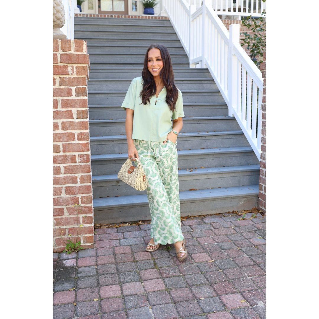 Woman in light green outfit standing on a set of stairs.