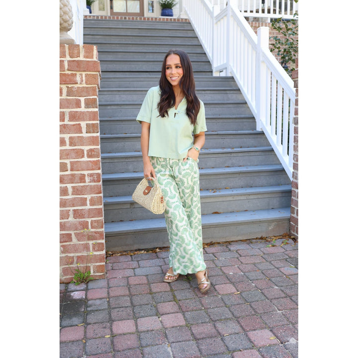 Woman in light green outfit standing on a set of stairs.