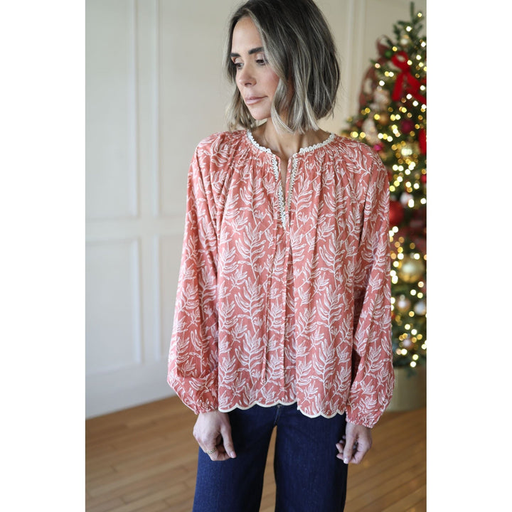 Woman wearing a red floral blouse in a room with a decorated Christmas tree.
