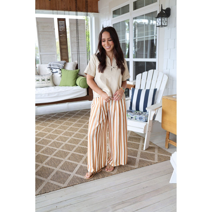 Woman standing on a porch with striped pants and cream top