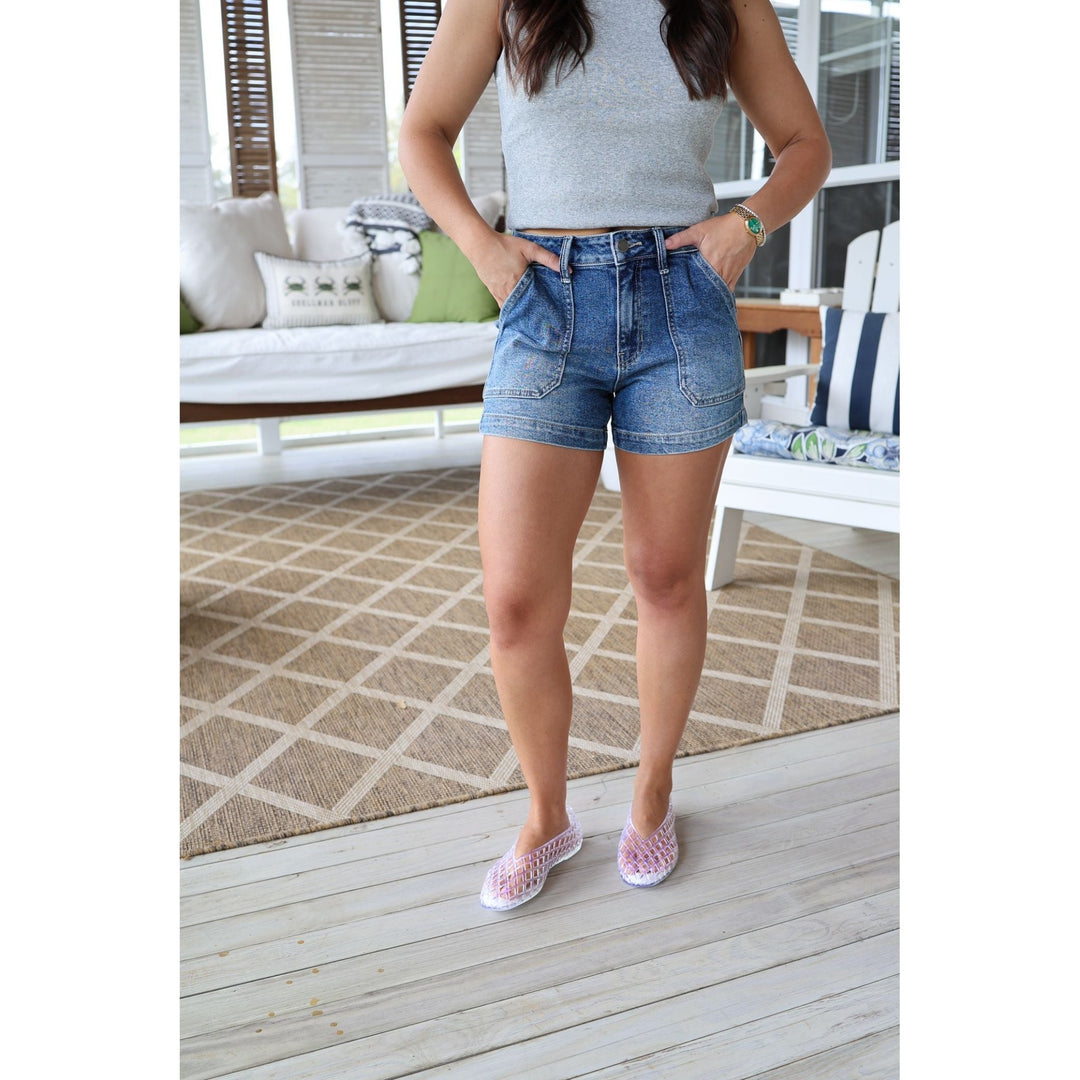 Person wearing denim shorts and a gray top on a wooden deck.