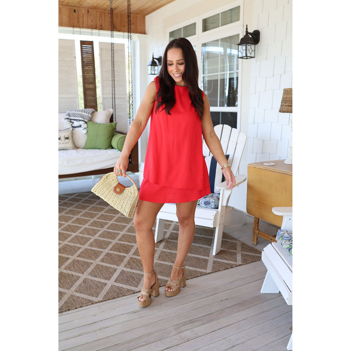 Woman in a red dress standing on a wooden deck with a white house in the background