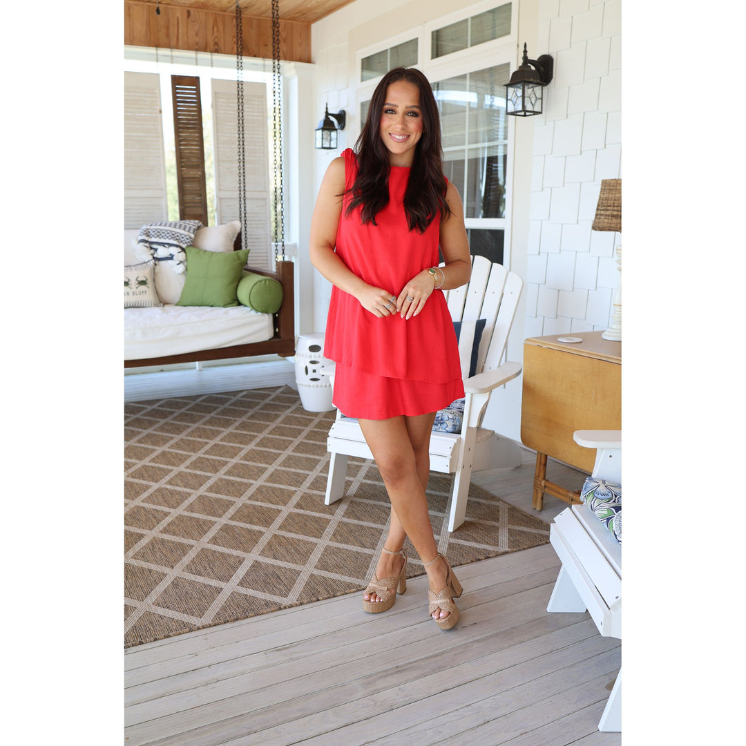 Woman in a red dress standing on a wooden deck with a white house in the background