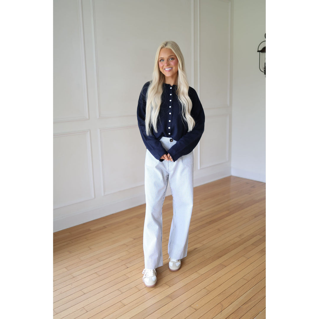 Woman wearing a navy sweater and striped pants 
