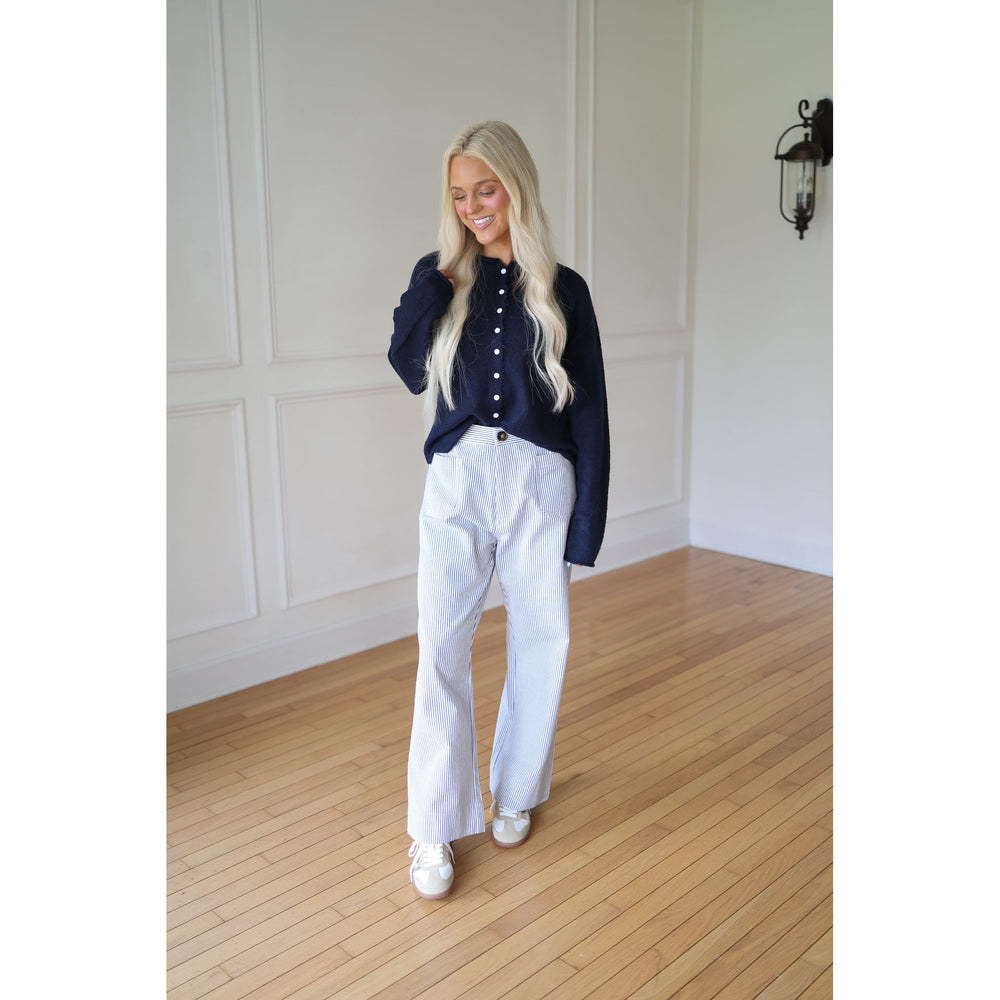 Woman wearing a navy blue sweater and striped pants 