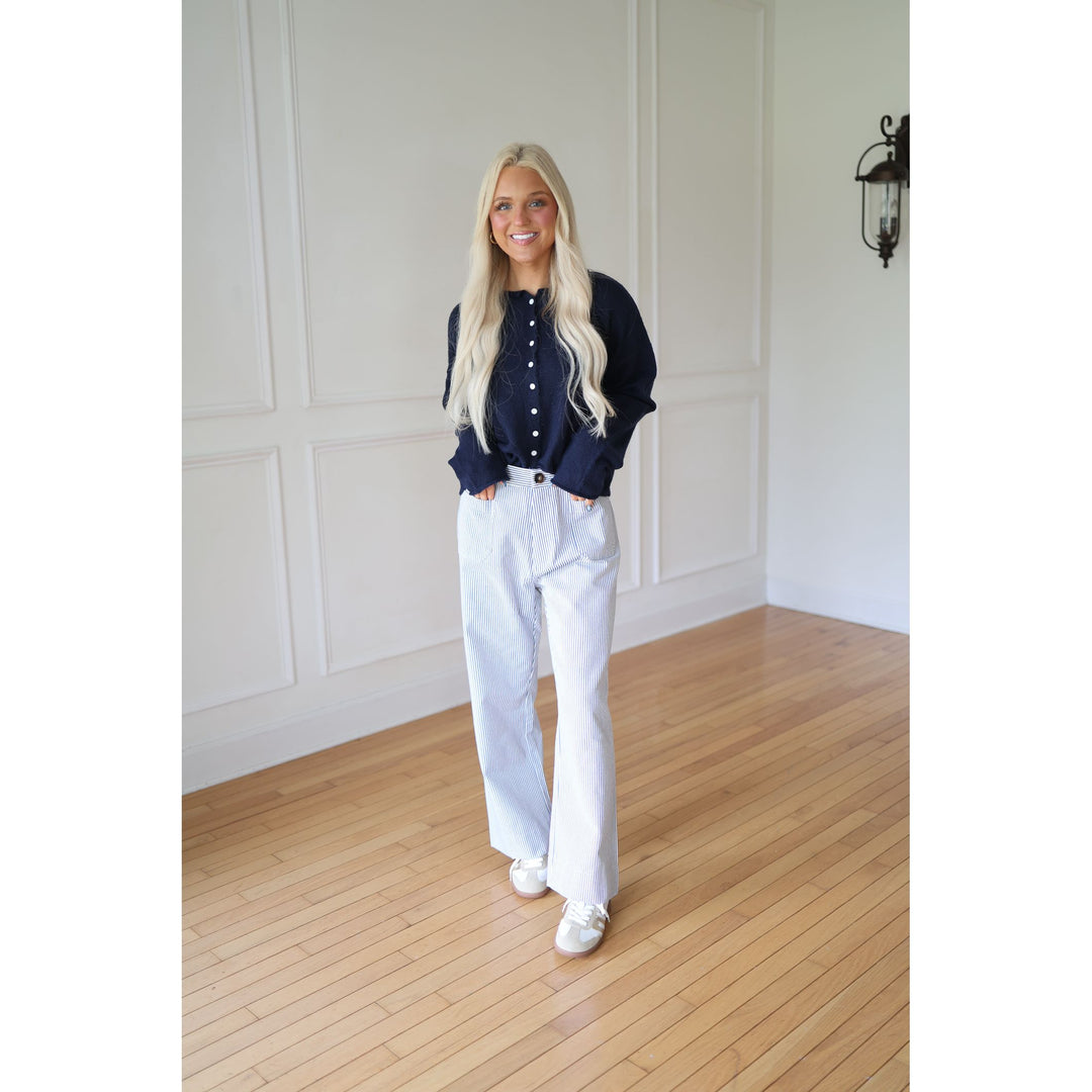 Woman wearing a navy sweater and striped pants 