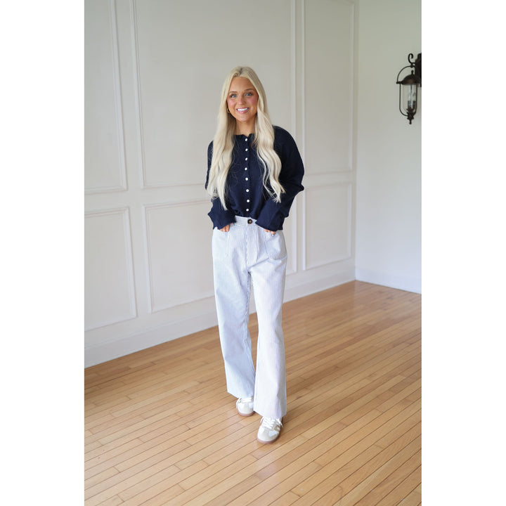 Woman wearing a navy sweater and striped pants 