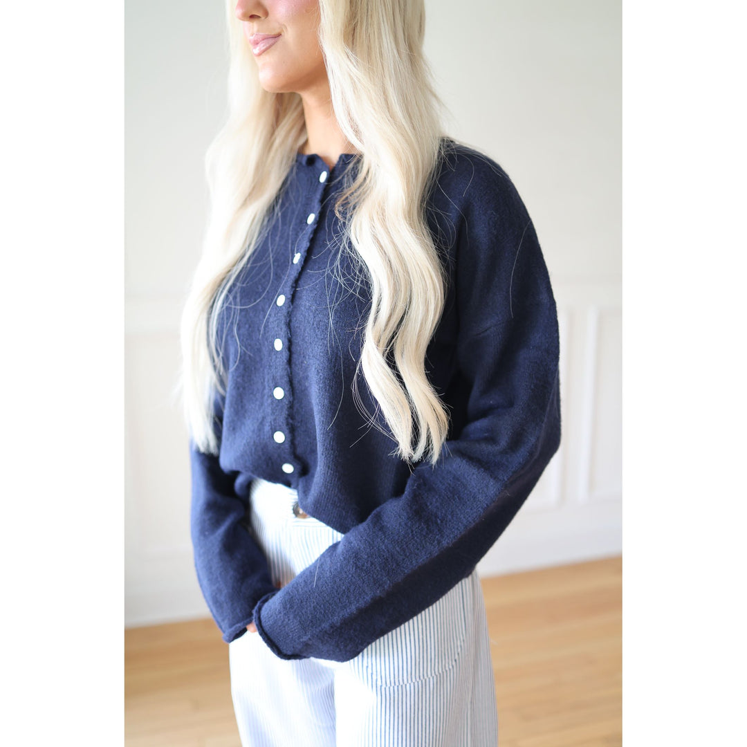 Person wearing a navy blue cardigan with white buttons