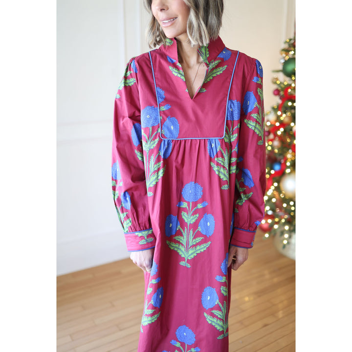 Woman wearing a wine floral dress standing in front of a Christmas tree.