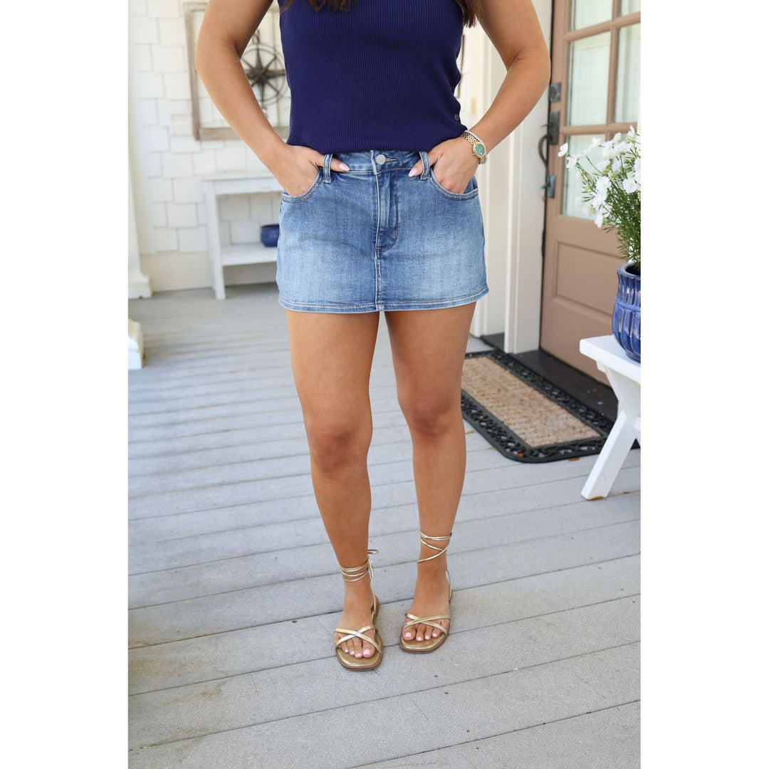 Person wearing a blue top and denim skirt on a wooden deck.