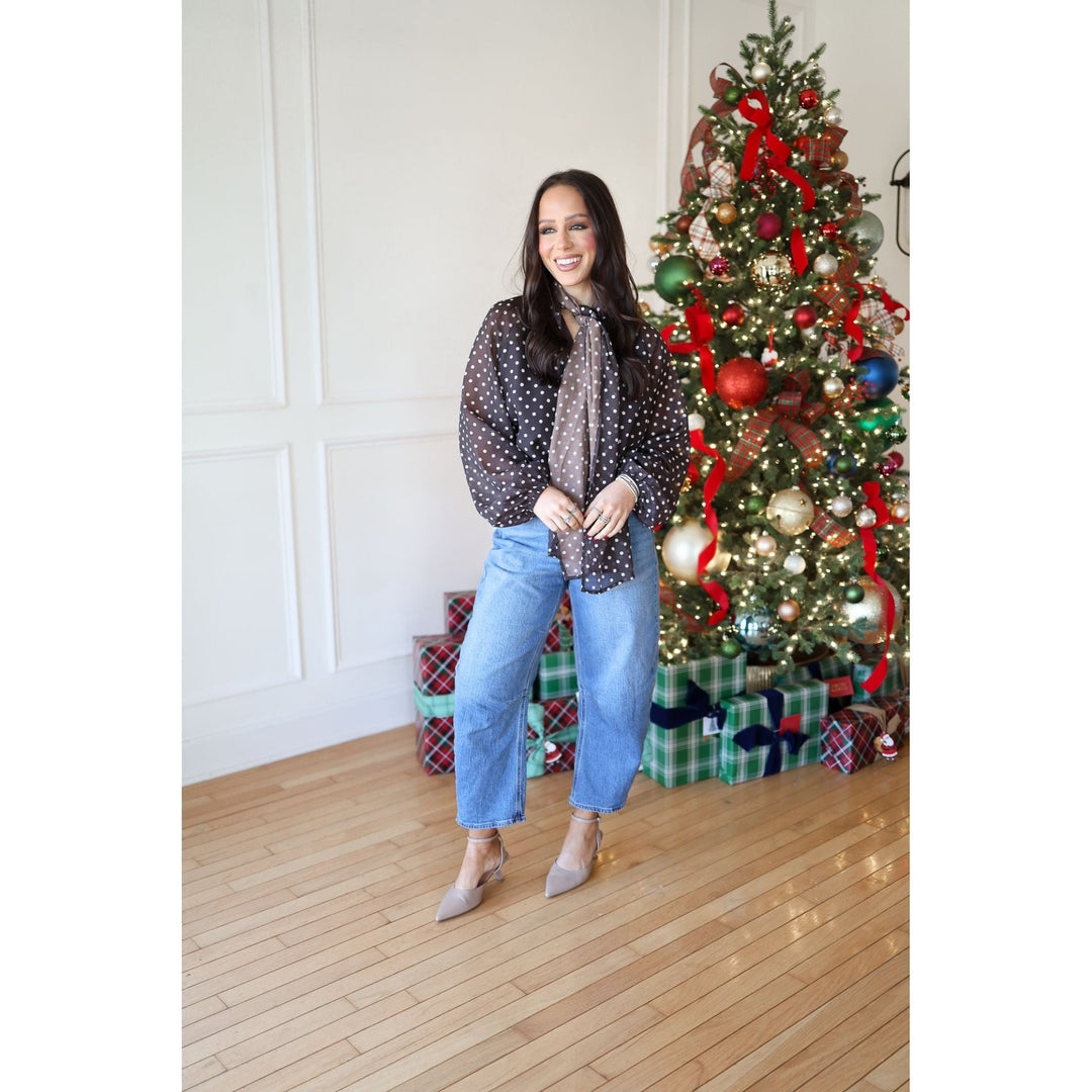 Woman standing in front of a decorated Christmas tree indoors.