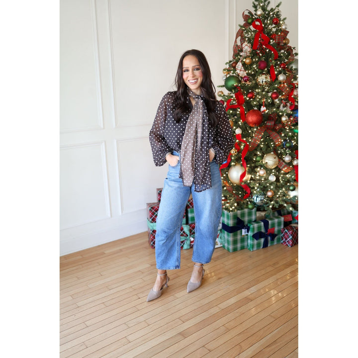 Woman standing in front of a decorated Christmas tree with presents underneath.