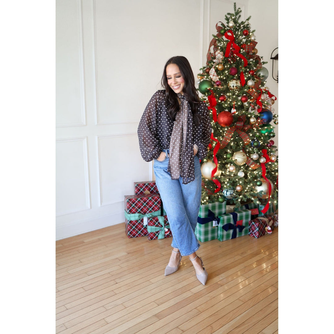 Woman standing in front of a decorated Christmas tree with presents underneath.