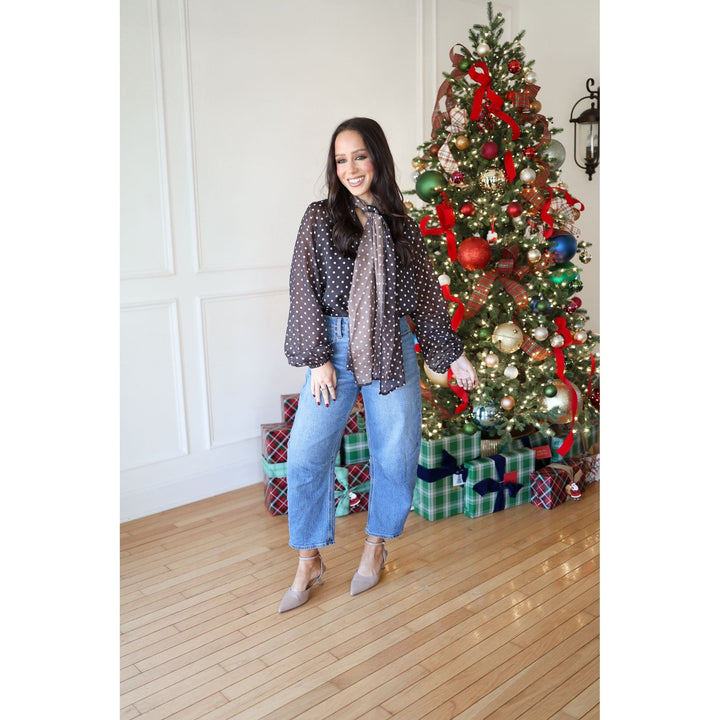 Woman standing in front of a decorated Christmas tree with presents underneath.