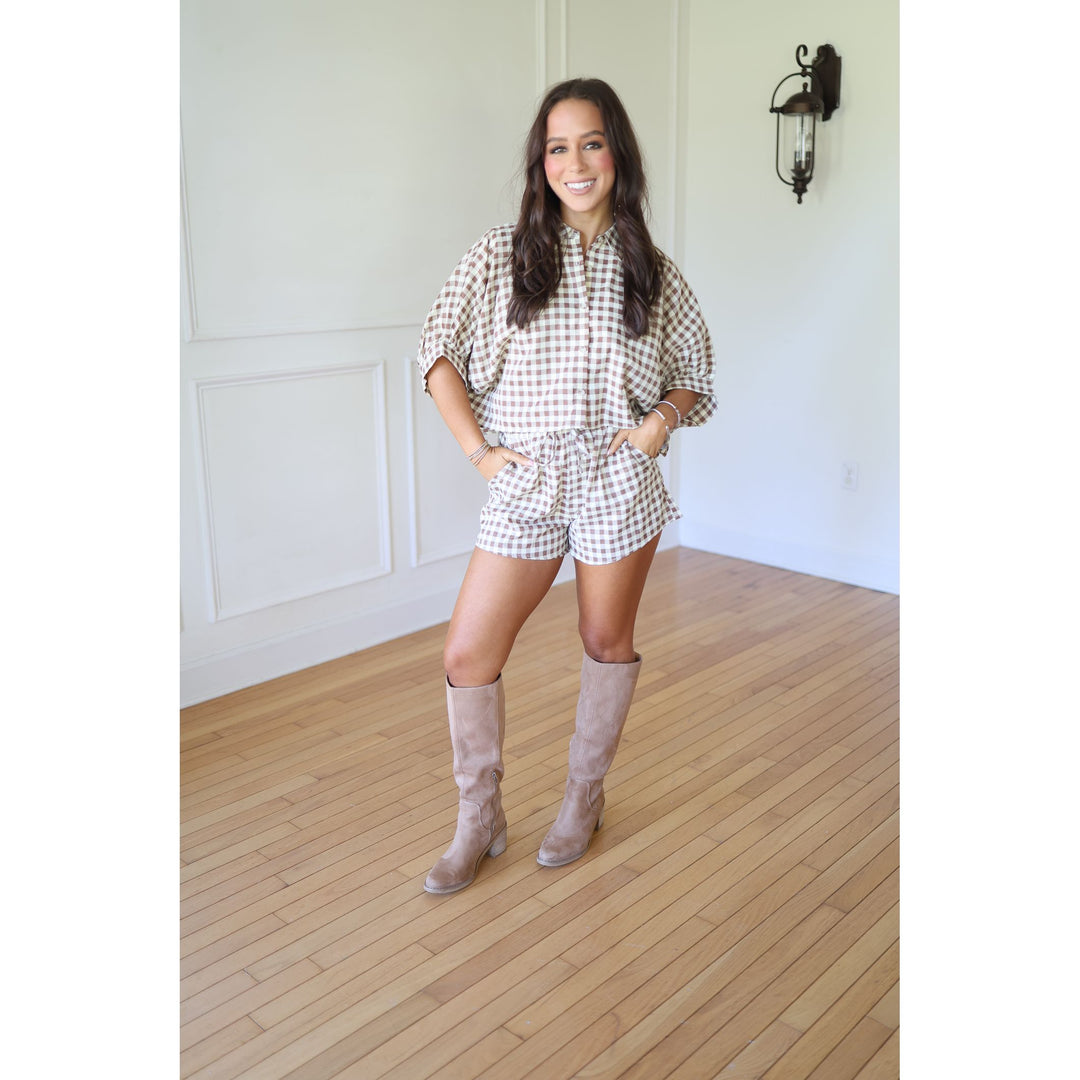 Woman wearing a checkered outfit with knee-high boots 