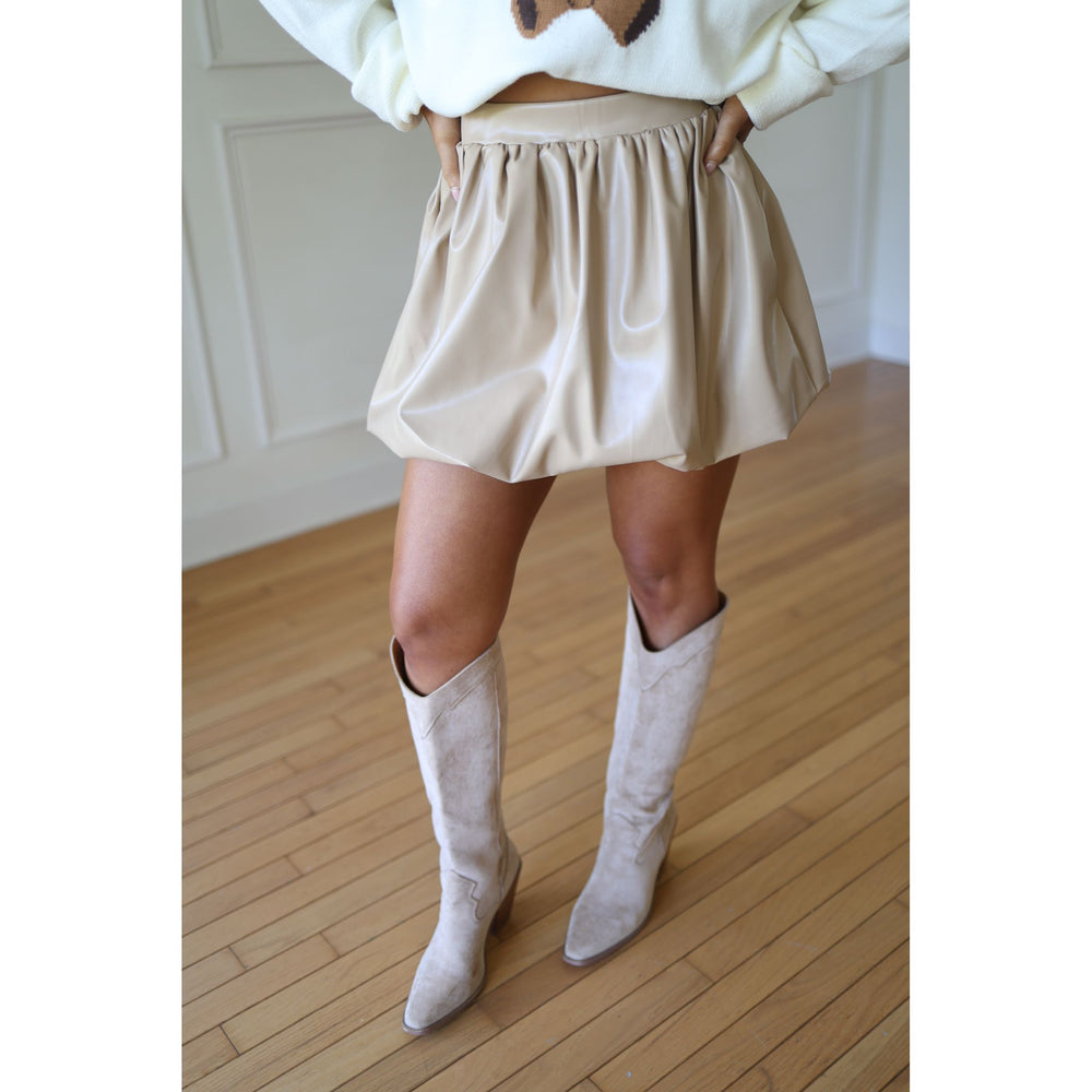 Person wearing a beige skirt and knee-high boots 