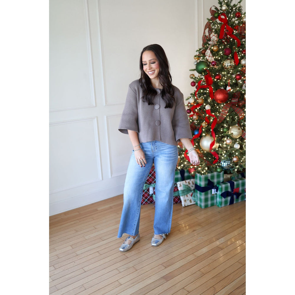 Woman standing in front of a decorated Christmas tree with presents underneath.