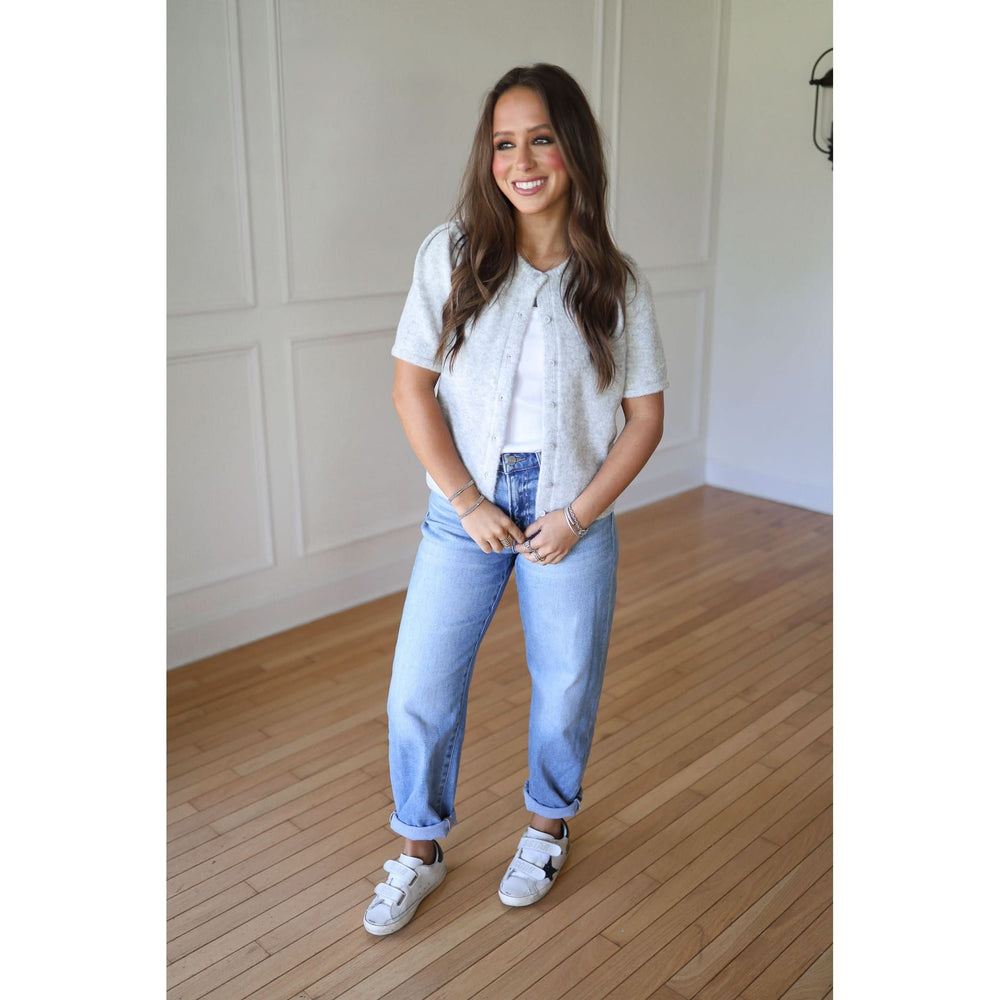 Woman wearing a gray sweater, blue jeans, and white sneakers 