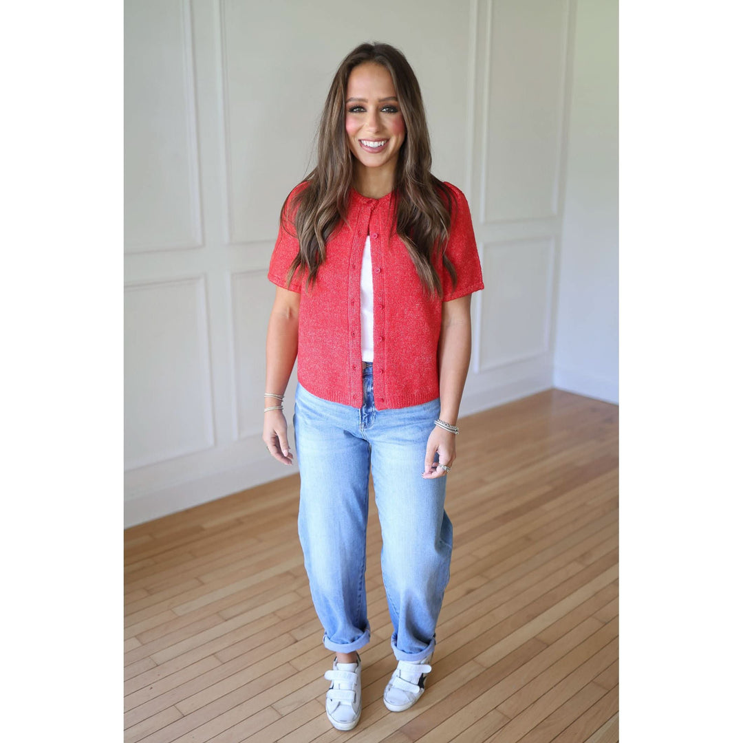 Woman wearing a red shirt and blue jeans standing in a room 