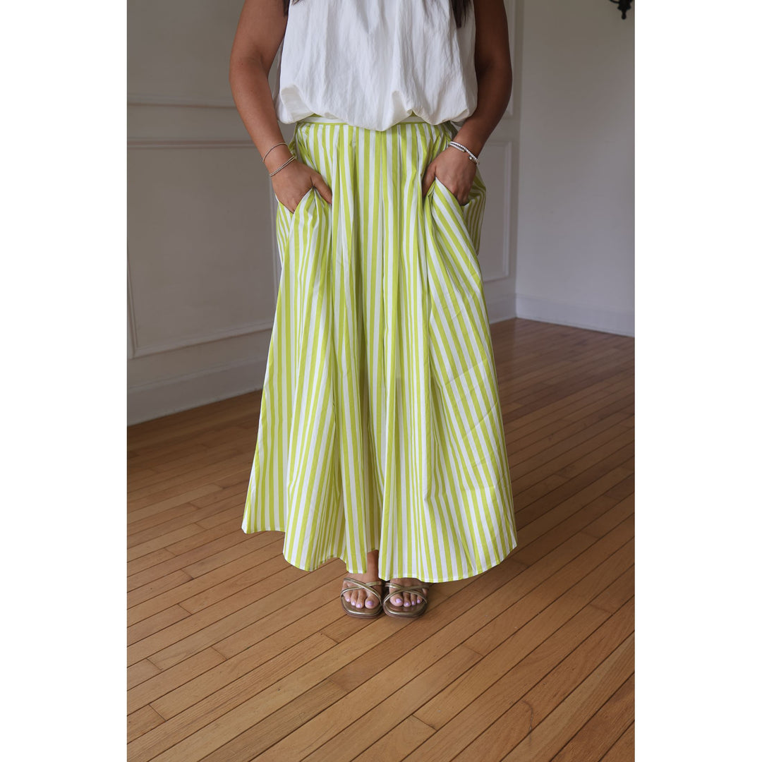Person wearing a white top and green and white striped pants on a wooden floor.