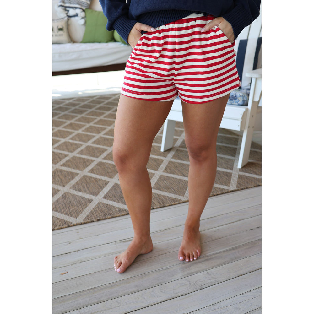 Person wearing red and white striped shorts on a wooden deck.