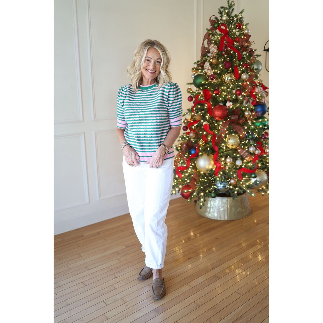 Woman standing in front of a decorated Christmas tree indoors.